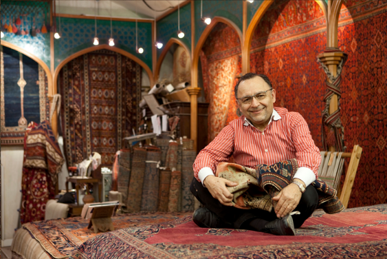 Architect Asghar Mollaian sitting among the rugs of his gallery