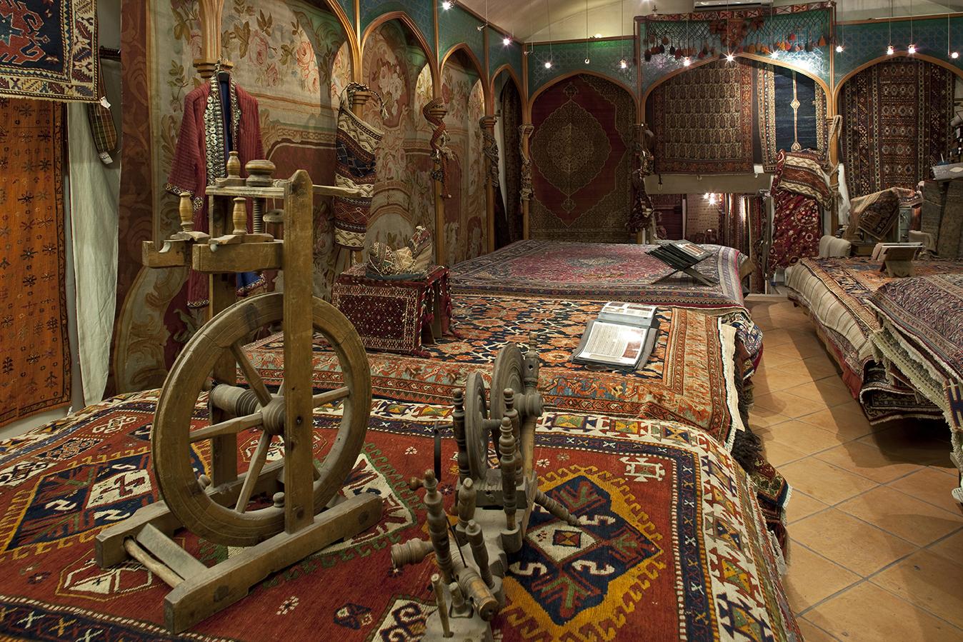 Inside the Mollaian gallery in Treviso: Oriental rugs on the walls and floor, and an antique wooden spinning wheel